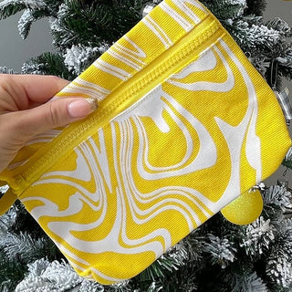 An image of a hand holding the beekman 1802 milk swirl wristlet bag.