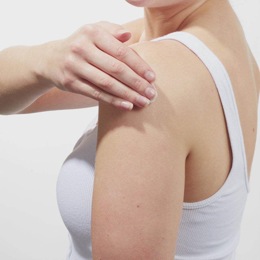 GIF of Models shoulder while wearing a white tank top and applying Beekman 1802's Sunshine Lemon Whipped Body Cream to her arm and rubbing it down.