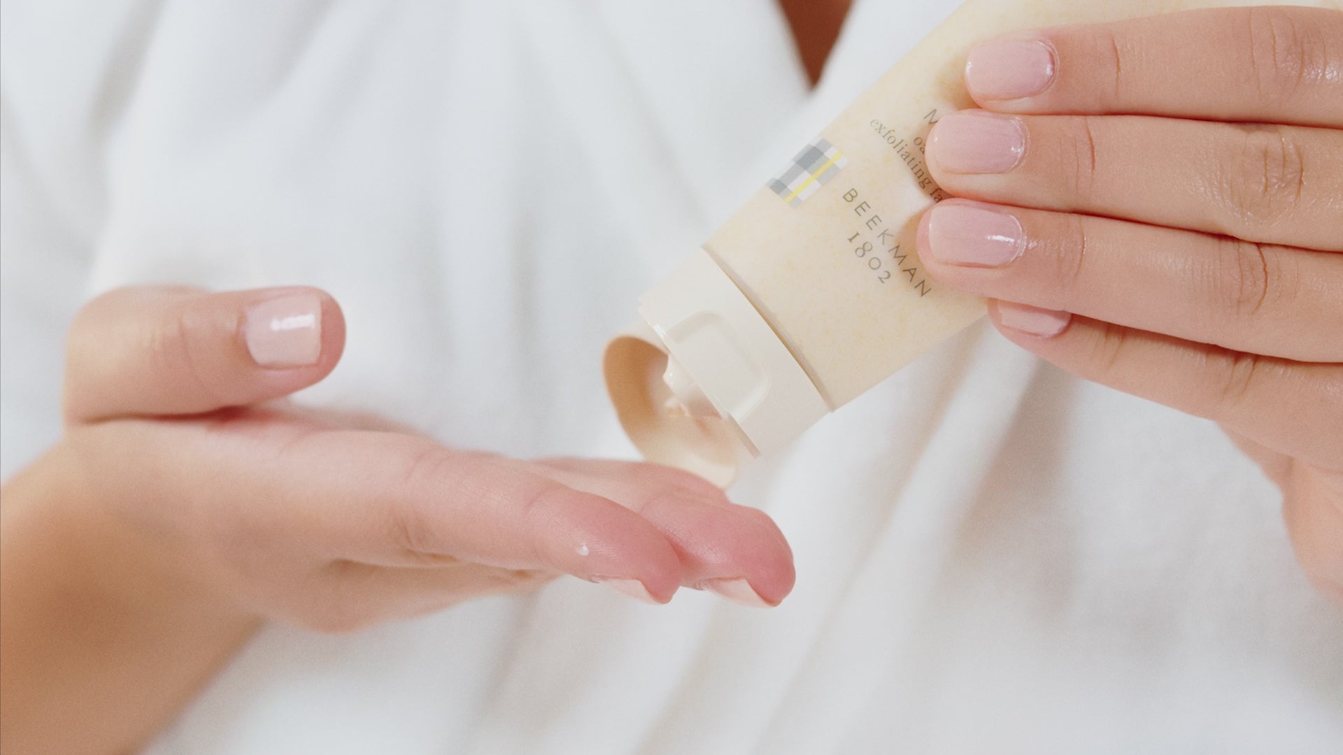 Video of model applying Beekman 1802's Milk Scrub Oat + Goat Milk Exfoliating Facial Cleanser, with text explaining how to use the cleanser and benefits. 