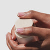 Video of two hands holding the beekman 1802 bloom cream daily moisturizer while pressing down on the cream to bloom.