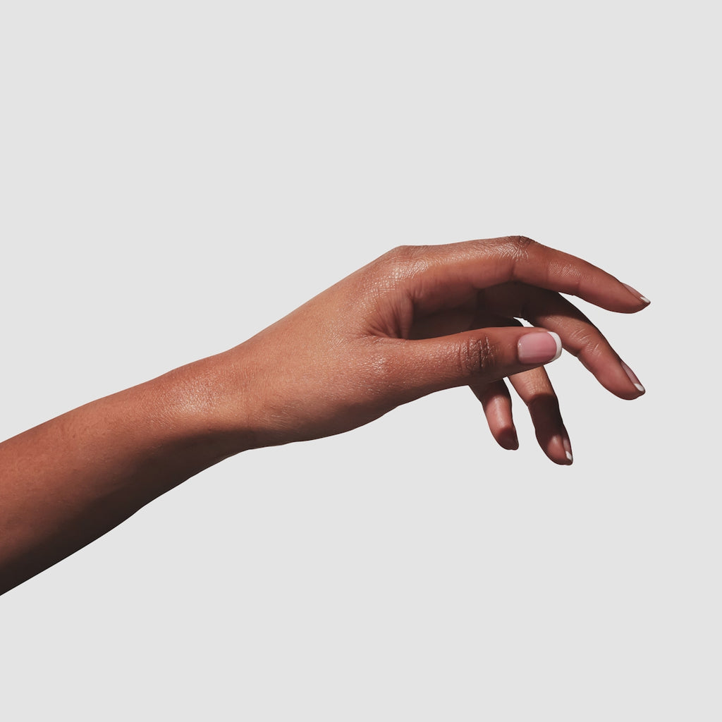 Up close GIF of hand applying hand cream to their other hand, on a white background.