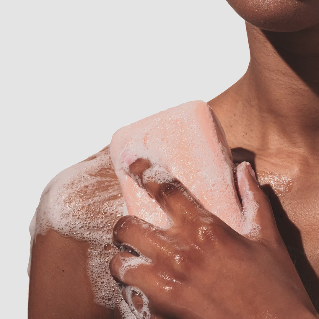 Model rubbing a sudsy beekman 1802 Honeyed Grapefruit 9 oz Goat Milk Soap onto their shoulder.