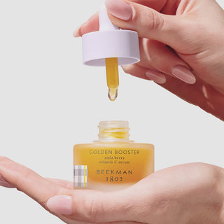 Video of hand holding the beekman 1802 Golden Booster Amla Berry Vitamin C Brightening Serum while holding the dropper in the other hand