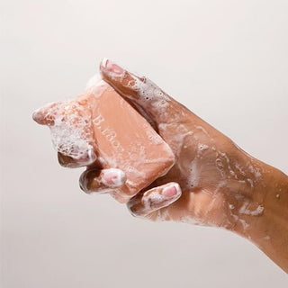 Hand holding a 3.5 oz Honeyed Grapefruit Bar Soap covered in suds.