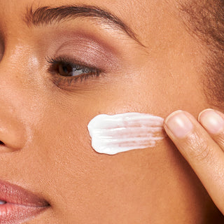 Up close shot of models cheekbone as she applies the bloom cream with two fingers. 