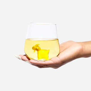 An image of a hand holding the Goatie Wine Glass that is filled with white wine.