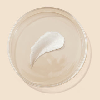A texture shot of the Beekman 1802 Buttermikl makeup melting cleaning balm in a petri dish.